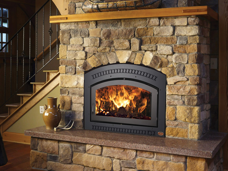 A warm fireplace in a stone wall next to a wooden staircase, with a vase on the mantle